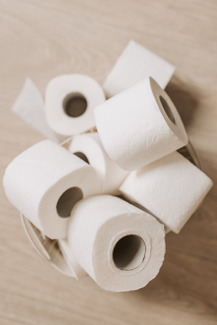 A basket filled with neatly arranged white toilet paper rolls, seen from above.