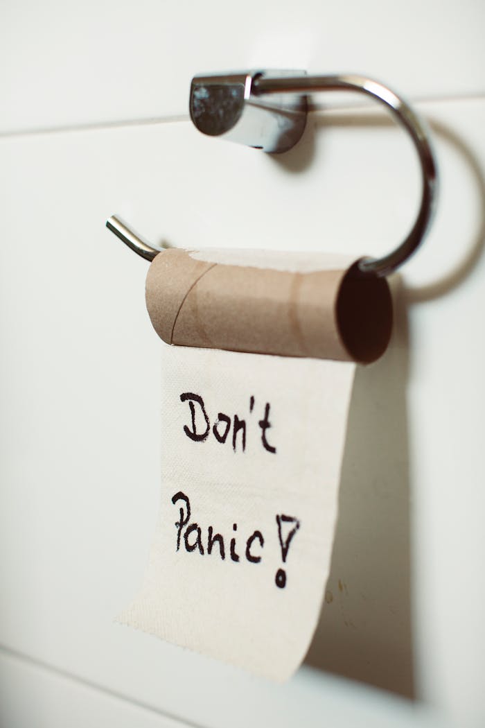 Close-up view of an empty toilet paper roll with a comforting u0022Don't Panicu0022 message hanging on a holder.