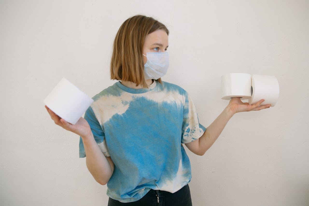 gallery-04 Woman with face mask holding toilet paper rolls indoors during pandemic.